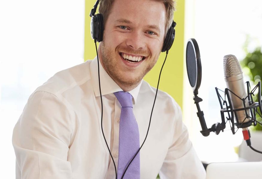 young-man-recording-a-podcast-smiling-to-camera-c-PQPF7YE.jpg
